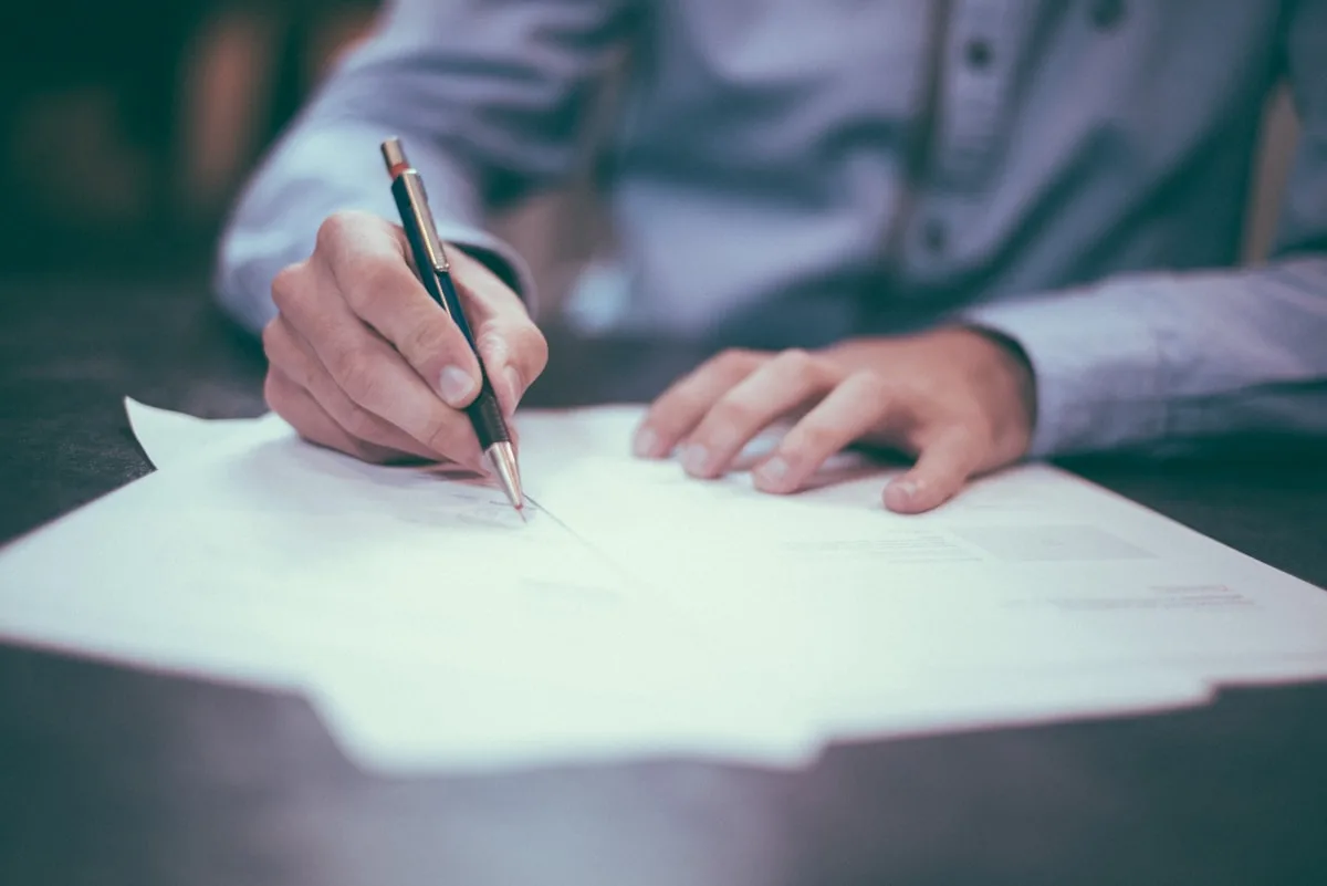 A pen resting on a printed document, part-way through being read line by line.