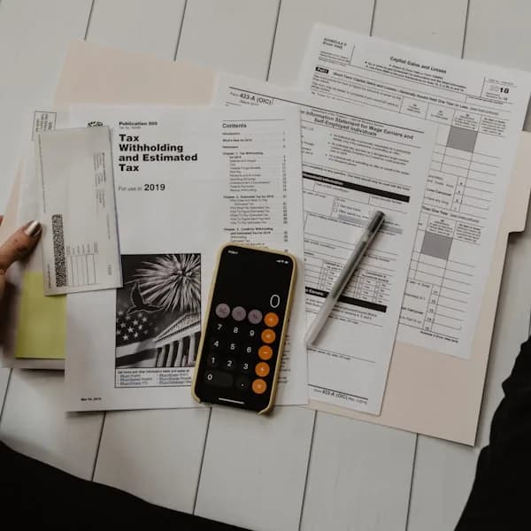 Printed forms and a calculator spread across a desk, part-way through being checked.