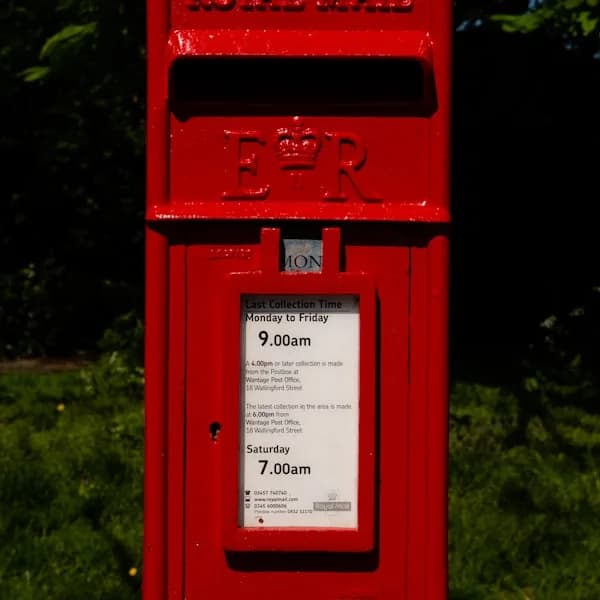 A red Royal Mail post box on a village street.